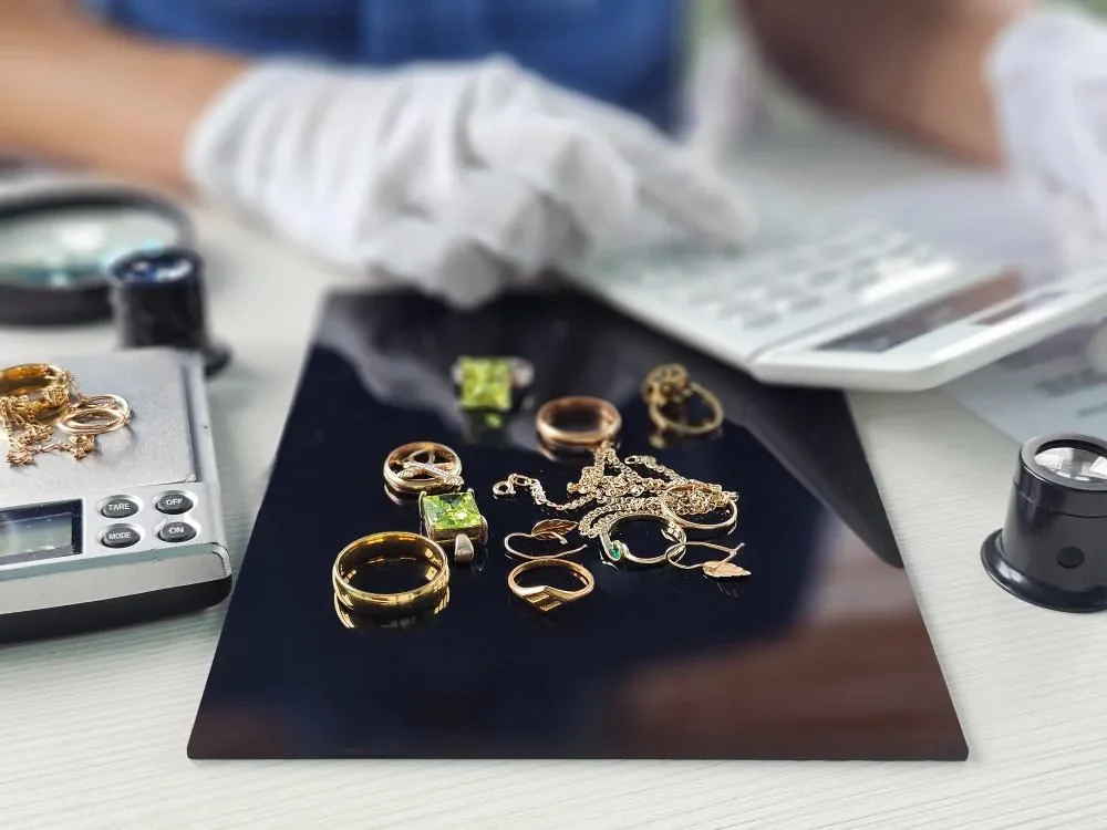 Gold jewellery organised on an assay tray alongside a scale